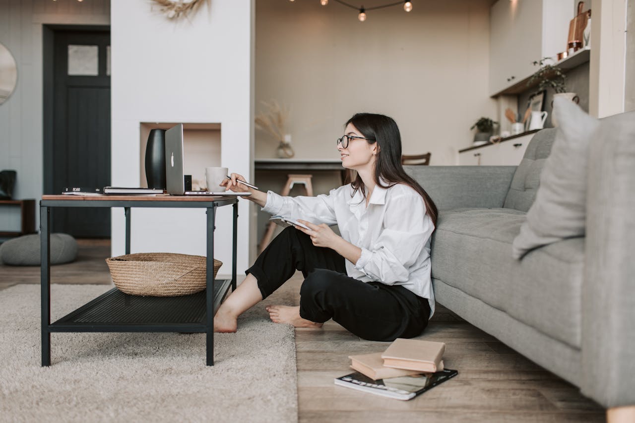 services-img Woman using a laptop while sitting on the floor of a cozy living room, epitomizing work-from-home lifestyle.