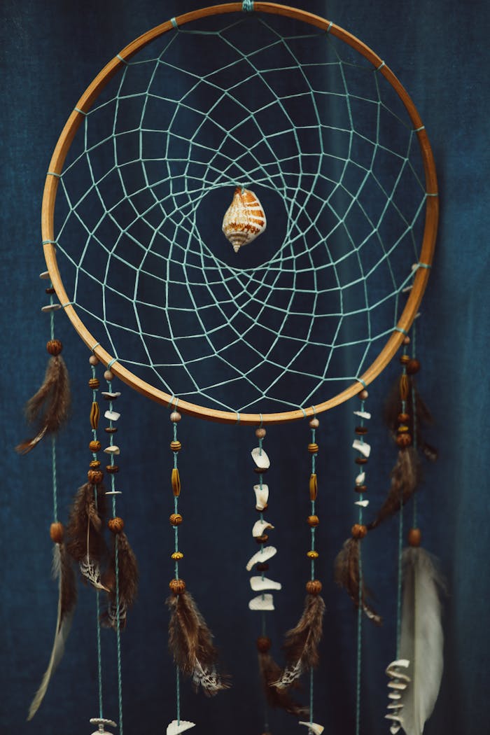about-img Artistic dream catcher featuring woven threads, beads, and feathers.